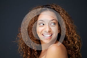 Beautiful young woman with curly hair laughing and looking away