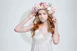 Beautiful young woman with curly red hair in flower wreath