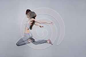 Beautiful young woman dancer jumping in studio