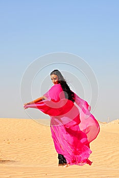 Beautiful young woman dancing in arabic desert