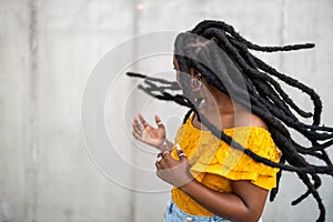 Beautiful young woman dancing in front of gray wall