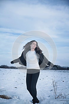 Beautiful young woman dancing on frozen snow winter field. Leisure, holiday, lifestyle and freedom concept. Vertical image