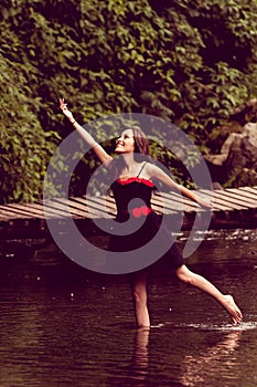 Beautiful young woman dancing in a lake forest