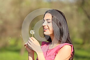 Beautiful young woman with dandelion in park