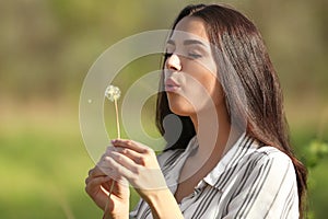 Beautiful young woman with dandelion in park