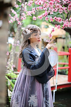 Beautiful young woman with dark blue Chinese lolita dress with Chinese garden