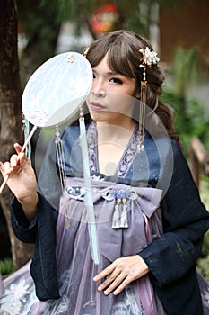 Beautiful young woman with dark blue Chinese lolita dress with Chinese garden