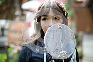 Beautiful young woman with dark blue Chinese lolita dress with Chinese garden