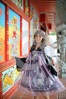 Beautiful young woman with dark blue Chinese lolita dress with Chinese garden