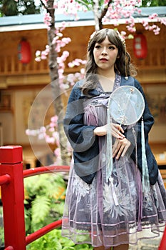 Beautiful young woman with dark blue Chinese lolita dress with Chinese garden