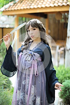 Beautiful young woman with dark blue Chinese lolita dress with Chinese garden