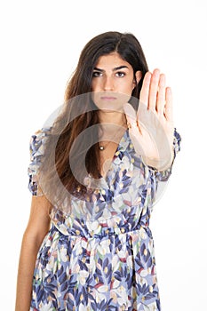 beautiful young woman with dark hair in white background with serious expression on face with palm gesture of hand signifying a