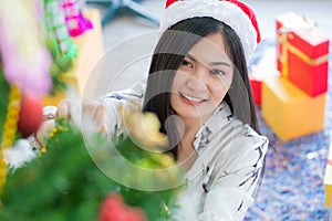 Beautiful young woman decorating xmas ornament on Christmas tree for Christmas and New Year holiday