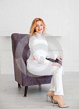 Beautiful young woman doctor in white uniform posing in a chair and looking at the camera