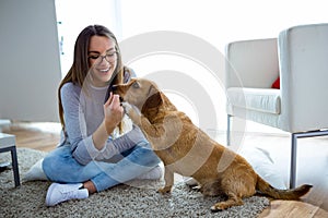 Beautiful young woman with dog playing at home.