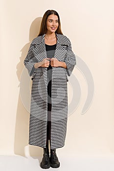 Beautiful young woman in dogtooth autumn coat and boots