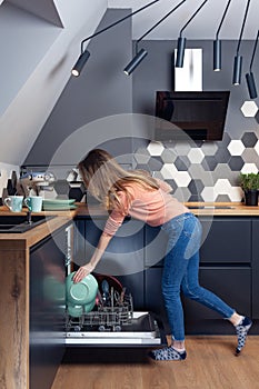 Beautiful young woman doing dishes in the kitchen