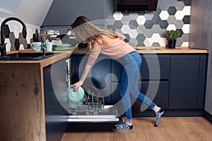 Beautiful young woman doing dishes in the kitchen