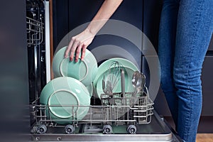 Beautiful young woman doing dishes in the kitchen