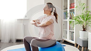 Beautiful young woman doing exercises on fitball at home. Concept of healthcare, sports and yoga at home