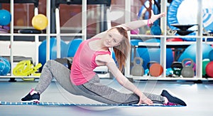 Beautiful young woman doing gimnastics on the floor