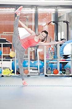 Beautiful young woman doing gimnastics on the floor