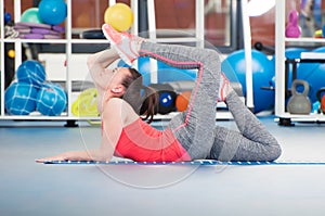 Beautiful young woman doing gimnastics on the floor