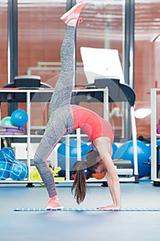 Beautiful young woman doing gimnastics on the floor