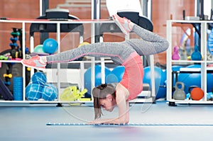 Beautiful young woman doing gimnastics on the floor