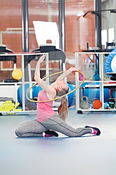 Beautiful young woman doing gimnastics on the floor with hoop