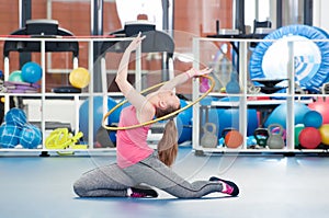 Beautiful young woman doing gimnastics on the floor with hoop