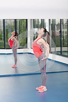 Beautiful young woman doing gimnastics on the floor with maces