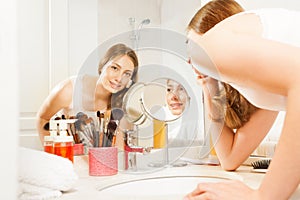 Beautiful young woman doing her makeup in bathroom