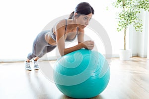 Beautiful young woman doing pilate exercise with fitness ball at home.