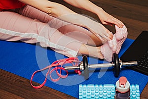 Beautiful young woman doing stretching exercise on floor at home, online training on laptop computer