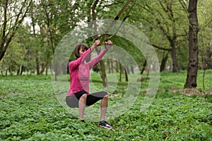 Beautiful young woman doing TRX exercise with suspension trainer