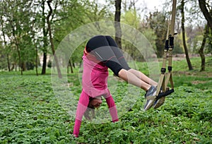 Beautiful young woman doing TRX exercise with suspension trainer