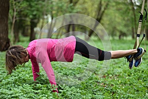 Beautiful young woman doing TRX exercise with suspension trainer