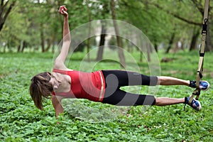 Beautiful young woman doing TRX exercise with suspension trainer