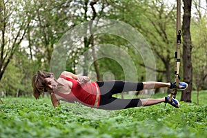 Beautiful young woman doing TRX exercise with suspension trainer