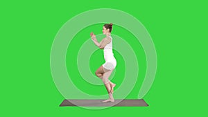 Beautiful young woman doing yoga exercise for ankles, calves, thighs, hips and shoulders, Eagle Pose, Garudasana on a