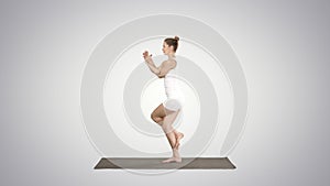 Beautiful young woman doing yoga exercise for ankles, calves, thighs, hips and shoulders, Eagle Pose, Garudasana on