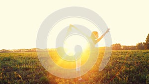 Beautiful young woman doing yoga exercise on the field during amazing sunset through the sun. Yoga concept.