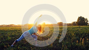 Beautiful young woman doing yoga exercise on the field during amazing sunset. Yoga concept.