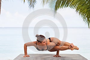 Beautiful young woman is doing yoga near the sea. Female gymnast doing stagged out hand stand