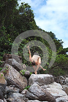Beautiful young woman is doing yoga near the sea. Female gymnast doing stagged out hand stand