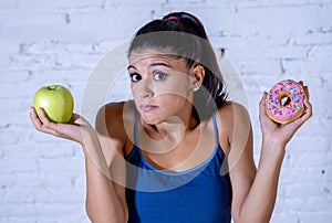 Attractive young woman on a diet deciding between an apple and a doughnut