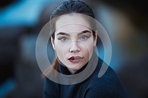 Beautiful young woman. Dramatic outdoor portrait of sensual brunette female with long hair. Sad and serious girl.