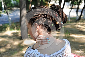 Beautiful young woman with dreadlocks hairstyle gathered in a ponytail, decorated assorted beads