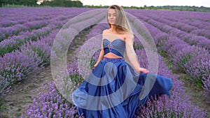 A beautiful young woman in a dress enjoying a stroll through the blooming lavender fields in Provence, France, in July
